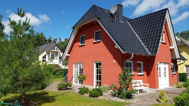 A red house with a black roof, white windows, and a number '29' on the side. - Schüßler house The red house - Schüßler (Trassenheide)