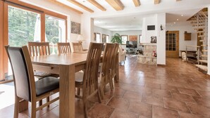 A spacious dining area with a wooden table and chairs, a television, and a stone fireplace. - Ferienhaus Oppach (Oppach)
