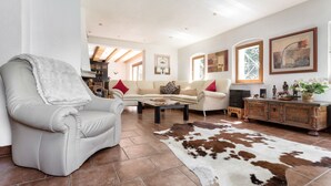 A spacious living room with a leather armchair, a sofa, a coffee table, and a cowhide rug. - Ferienhaus Oppach (Oppach)
