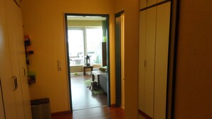 A hallway with wooden flooring, a green mat, a trash bin, and a door leading to a balcony with a view. - Ground floor apartment in apartment complex Fördeblick  (Laboe)