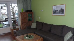 A living room with a wooden coffee table, a sofa, and a cabinet with glass doors. - Ground floor apartment in apartment complex Fördeblick  (Laboe)