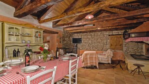 A rustic dining area with a stone wall, wooden beams, and a checkered tablecloth. - Erisa in Trošti (Haus für 6 Personen) (Pazin)