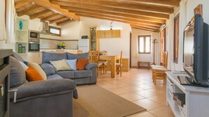 A cozy living room with a sofa, TV, and wooden beams on the ceiling. - Holiday house with pool in the heart of Mallorca (Sant Joan)