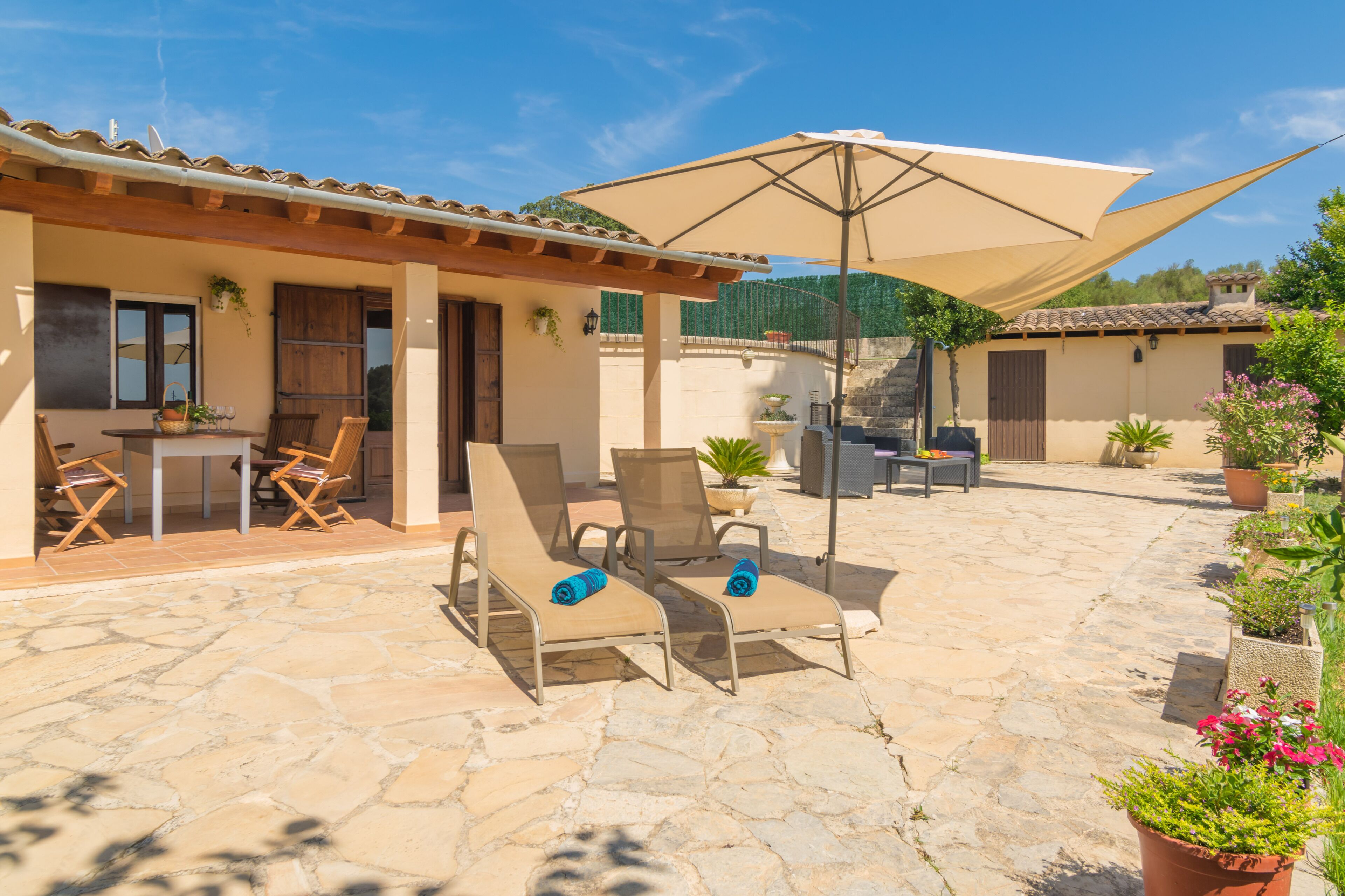 A patio with stone flooring, outdoor seating, and potted plants.