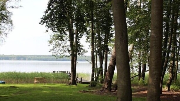 A lakeside park with a bench and a wooden deck.