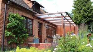A brick house with a covered patio area, a window, and a chair.