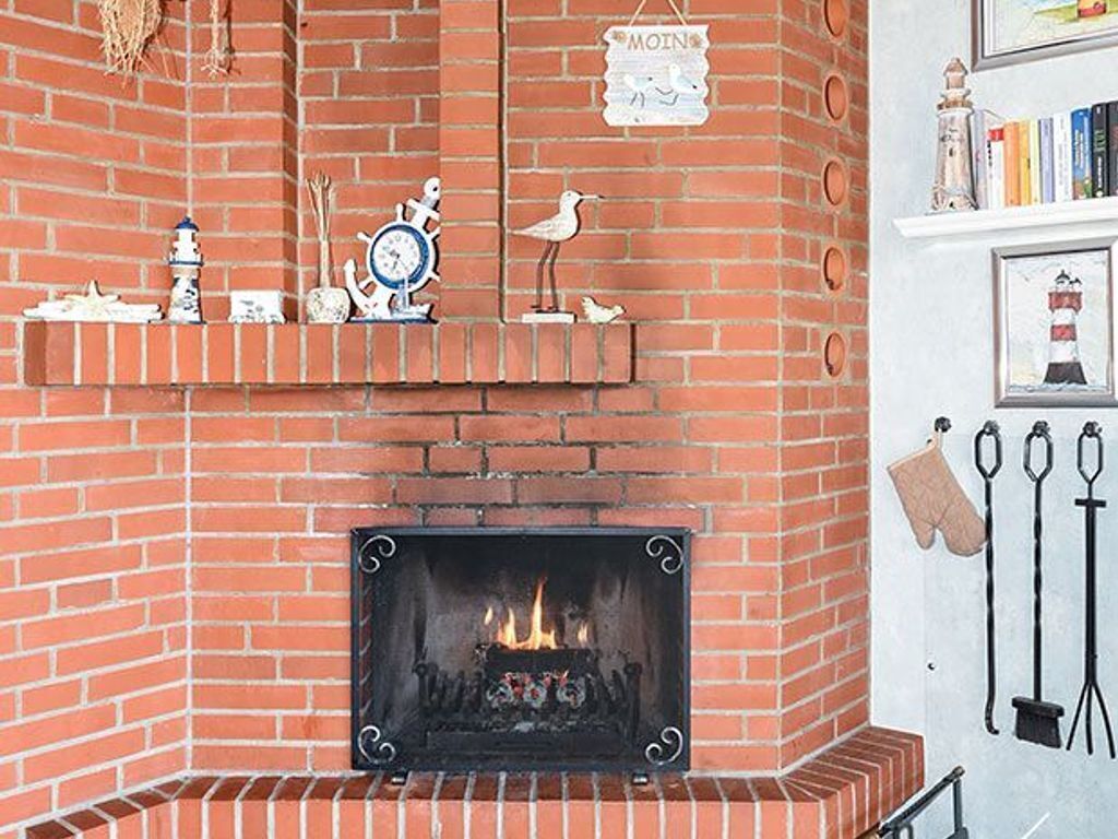 A brick fireplace with a fire, decorative items, and a sign above it.