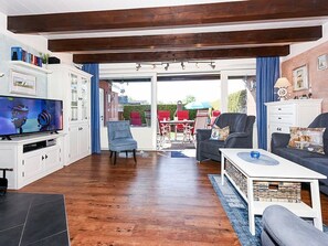 A living room with a TV, seating, and a view to the outside.