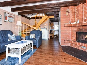 Ein Wohnzimmer mit Kamin, Treppe und einem Hund.
