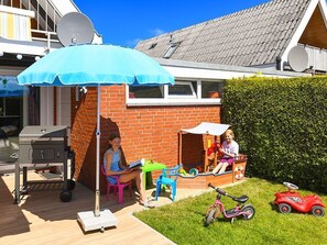 A patio area with a grill, a table, and a blue umbrella.