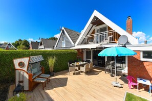 Ein Haus mit Terrasse, Gartenmöbeln und einer Satellitenschüssel.