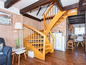A wooden staircase in a room with a desk, chair, lamp, and a small table with a plant.