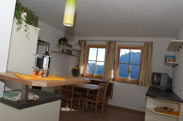 Eine kompakte Küche mit Essbereich, einem Fernseher und einem Fenster mit Blick auf die Berge.
