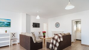 A living room with two sofas, a TV, a clock, and a fireplace. - Holiday Home 'Villa Charco del Sultán' with Wi-Fi, Pool, Terrace & Garden (Conil de la Frontera)
