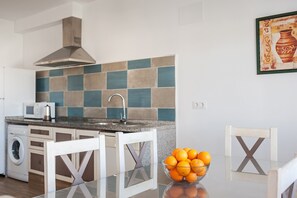 A kitchen with a microwave, washing machine, and a tiled backsplash.