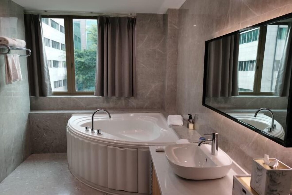 Un baño moderno con una bañera independiente, un tocador con lavabo y un espejo grande.