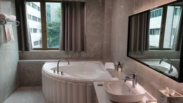 A modern bathroom with a freestanding bathtub, a vanity with a bowl sink, and a large mirror.