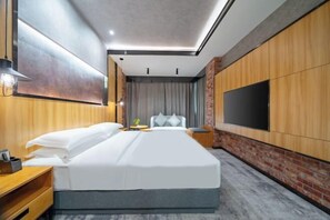 A modern hotel room with a large bed, wooden paneling, a flat-screen TV, and a small side table. - Changhong International Hotel (Mianyang)