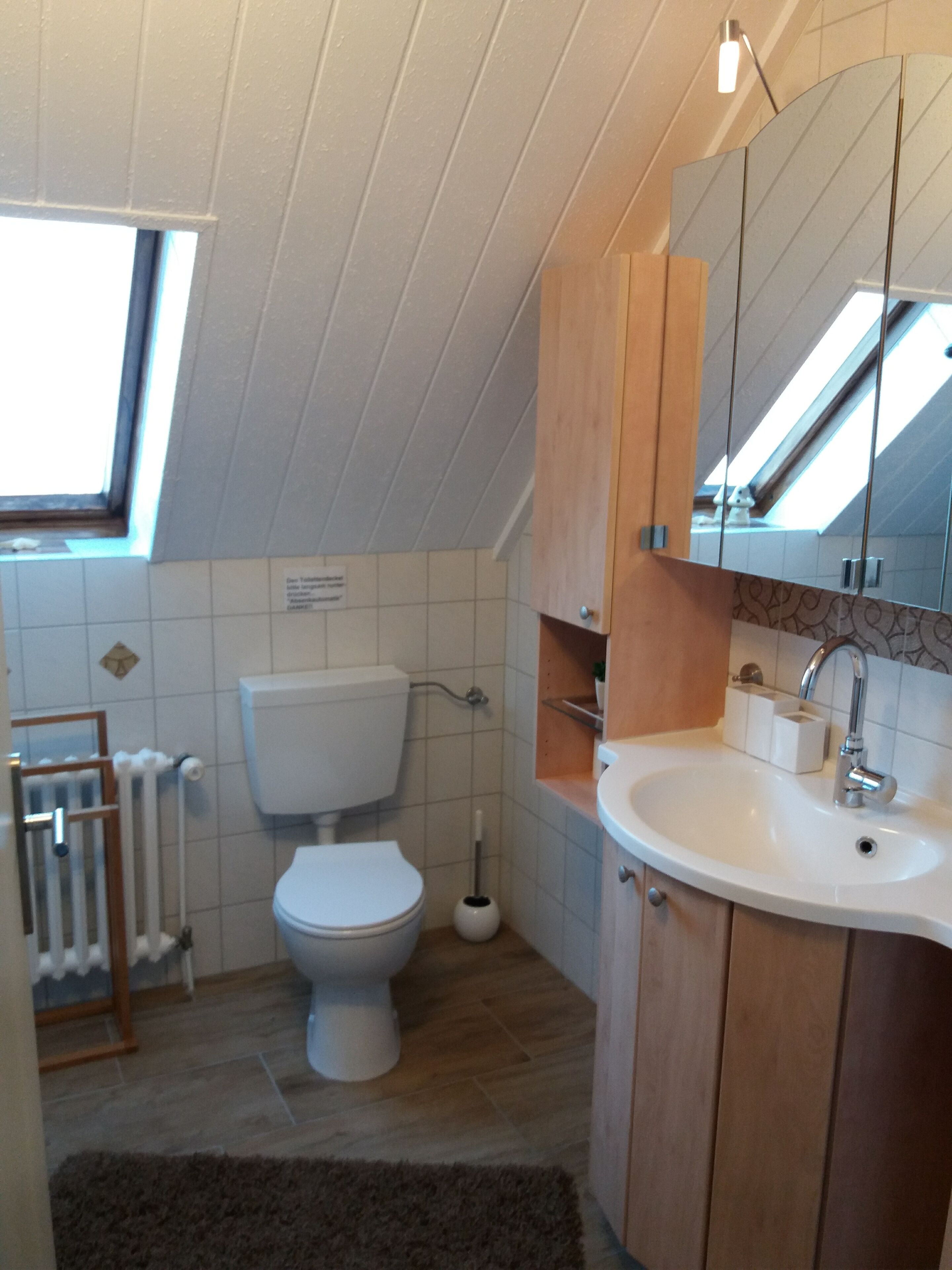 A compact bathroom with a toilet, sink, and wooden cabinets.