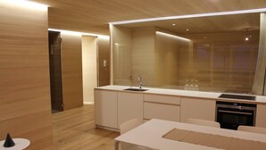 Une cuisine moderne dotée d’un grand îlot central, de meubles blancs et d’un four encastré.