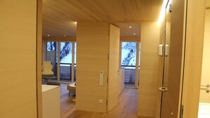 Un intérieur moderne avec des planchers et des murs en bois, une porte visible et un banc à l’arrière-plan.