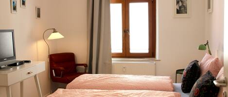 A bedroom with a bed, a desk, a chair, a lamp, and a window.