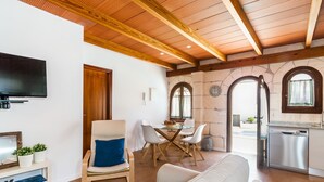 A modern living room with a wooden ceiling, a flat-screen TV, a dining area with a glass table, and a kitchen with a dishwasher. - Can Xisco (Sineu)