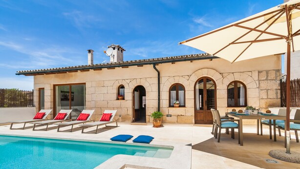 A poolside area with lounge chairs and a dining table. - Can Xisco (Sineu)