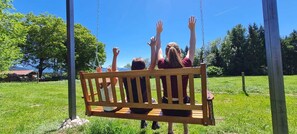 A wooden swing set in a grassy area with trees in the background.