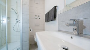 A modern bathroom with a glass-enclosed shower, a white sink, and a mirror. - 5 large apartments, for a maximum of 4 people in an idyllic location near Munich (Billingsdorf)