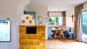 Ein gemütliches Wohnzimmer mit Kamin, einem Essbereich mit Tisch und Stühlen sowie einem großen Fenster mit Vorhängen.