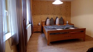 Ein Schlafzimmer mit einem hölzernen Bett, einem Nachttisch, einer Lampe und einem Fenster mit Vorhängen.