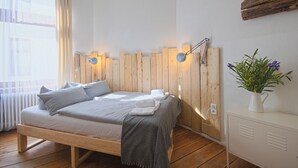 Makuuhuoneessa on puinen sänky, yöpöydällä lamput, valkoinen lipasto ja ruukussa oleva kasvi.