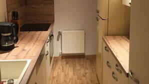 Eine kleine Küche mit Holzbalken, einem eingebauten Herd, einem Kühlschrank und einer Kaffeemaschine.