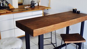 A modern kitchen with a wooden table, stools, and a hanging light fixture. - Old forge in a listed courtyard (Messerich)