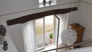 A staircase leading to a second floor with a view of a garden through a glass door. - Old forge in a listed courtyard (Messerich)