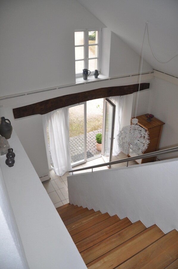 A staircase leading to a second floor with a view of a garden through a glass door.