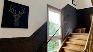A staircase with wooden steps and a metal handrail, leading to a landing with a black wall and a framed picture. - Villa Landenberger Metzingen near Outlet City Apartment Annemarie (Metzingen)