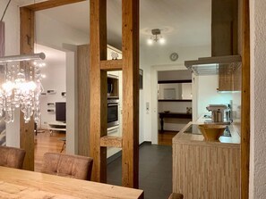 A modern kitchen with wooden accents, a dining area with a chandelier, and a visible kitchen counter. - Villa Landenberger Metzingen near Outlet City Apartment Annemarie (Metzingen)
