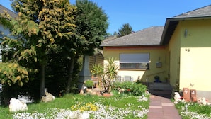 Une maison d’habitation avec un jardin et un chemin menant à l’entrée.