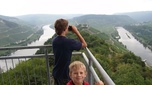Une personne prend une photo d’une vallée fluviale depuis un point de vue élevé.