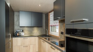 A modern kitchen with wooden cabinets, stainless steel appliances, and a window with decorative curtains. - Châtel Portes du Soleil Free MultiPass 3-Star Apartment PDS Chairlifts 400 meters away (châtel)