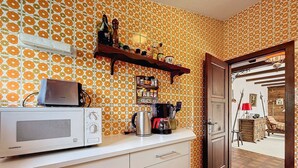 Una cocina con microondas, cafetera y estantes con diversos objetos.