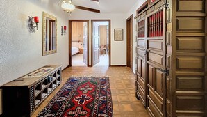 Un pasillo con alfombra estampada, armarios de madera y un ventilador de techo.