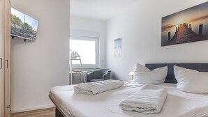 Een hotelkamer met een bed, een bureau, een stoel, een raam en een schilderij aan de muur.