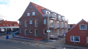 Een gebouw van rode baksteen met meerdere verdiepingen, balkons en een schuin dak.