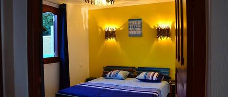 A bedroom with a bed, a window, and a wall with a poster.
