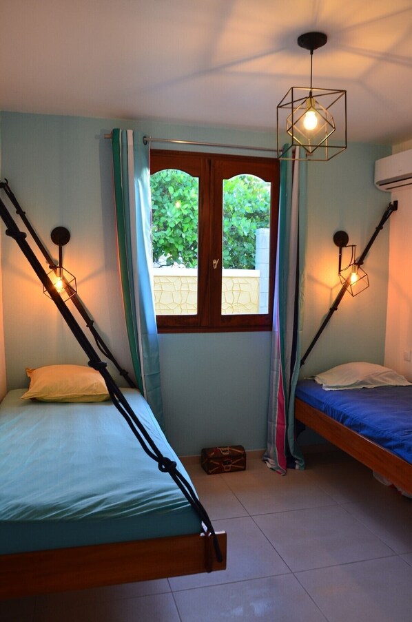 Un dormitorio con dos camas, una ventana con cortinas y dos lámparas fijadas a la pared.