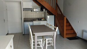 A compact kitchen with a dining table, chairs, a microwave, a coffee maker, and a dishwasher.