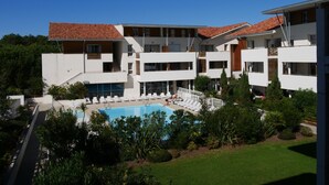 A modern multi-story building with a swimming pool surrounded by greenery.